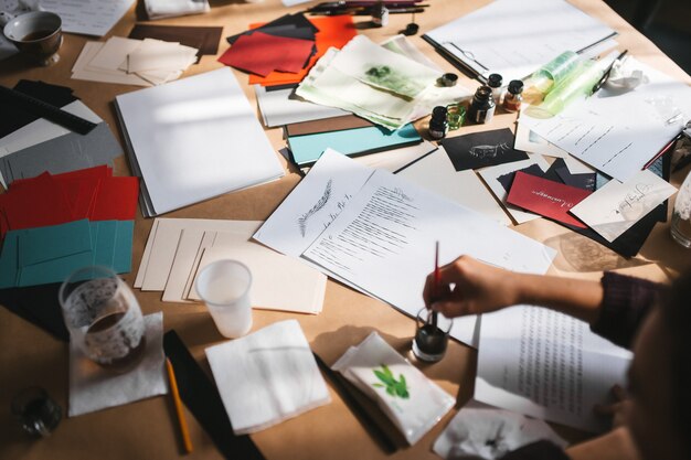 Creative mess on the table of an artist who practices writing with fountain pen