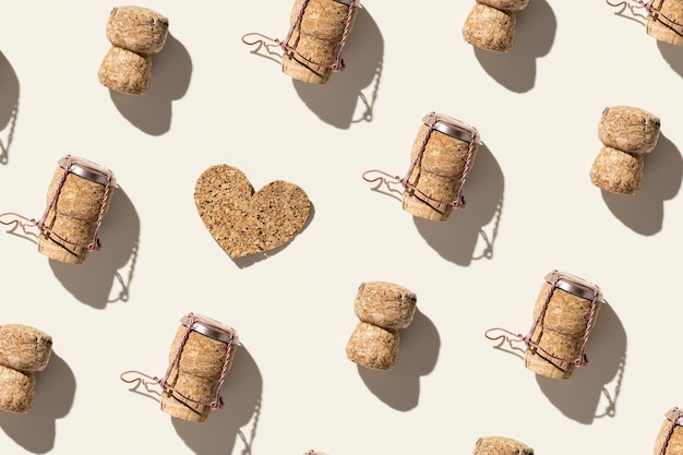 Creative pattern with champagne cork and heart on beige background with hard light and shadows