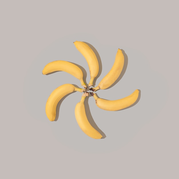 Creative pattern with yellow bananas on gray background. Minimal flat lay composition.