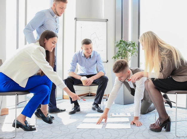 Creative people looking at project plan laid out on floor Business associates discussing new project plan in modern office