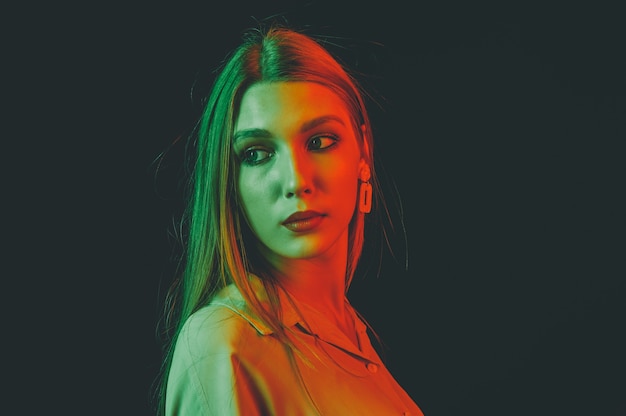 Creative portrait of a beautiful female model close-up. orange and green lighting in the Studio.