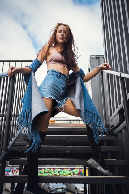 Creative portrait of a red-haired woman in a short  shorts and top. Design concept. Romantic portrait of young woman posing in urban area