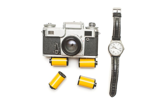 Creative retro concept from the past. Old retro film camera and photo film roll with mechanical men's watch isolated on white background. Flat lay, top view