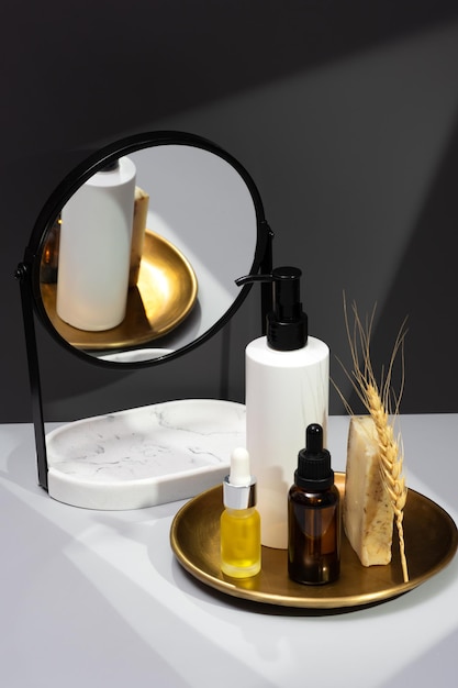 Creative still life with natural cosmetics Set of essential oils handmade soap and mirror on a dark gray background The concept of selfcare and organic products Reflection in the mirror