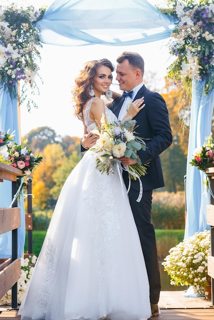 Creative stylish wedding ceremony elegant curly bride and groom outdoors on the background the lake