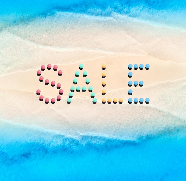 Creative text made from umbrellas on empty sandy beach and blue sea at sunny day Aerial view of sea coast and text Summer sale and discount Background Top view from drone of clear water sandbank