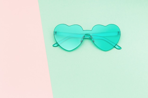 Creative top view with modern sunglasses on paper background. Heart shaped eyeglasses pastel colored. Minimal geometry summer concept. Flat lay with copy space.