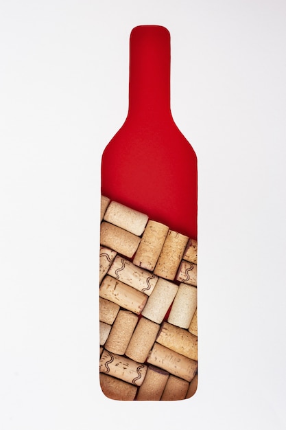 Creative wine bottle with wooden corks inside. Form of bottle in front on paper  Concept for winery, degustation bar. Flat lay with empty space for text.