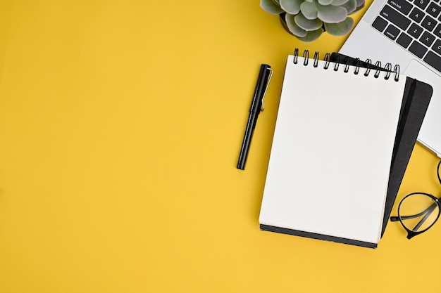 Creative workspace top view with blank empty page notepad and space on yellow background