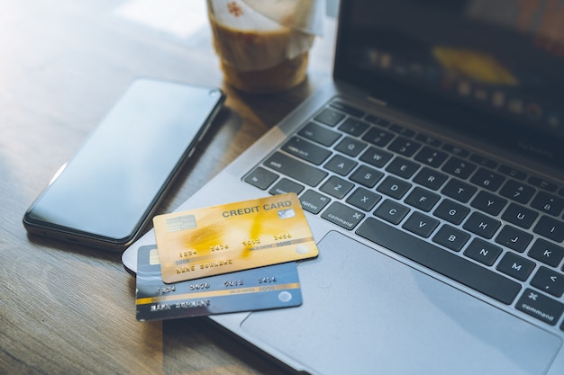 Credit card of laptop computer,smartphone and coffee cup on wooden background,Online banking Concept