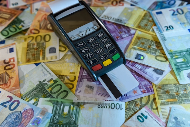 Credit card in terminal over euro banknotes