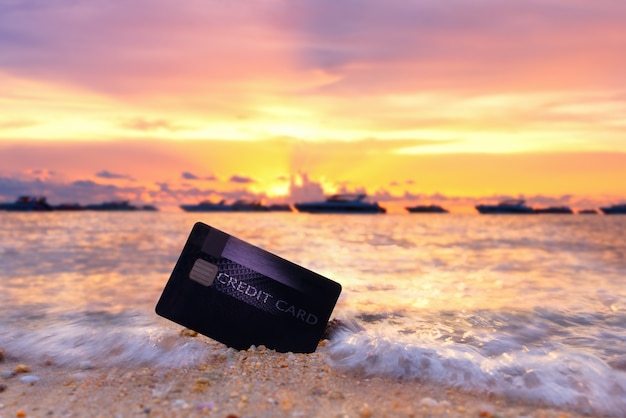 Credit card on the tropical beach in Pattaya at sunset, travel and holiday concept.