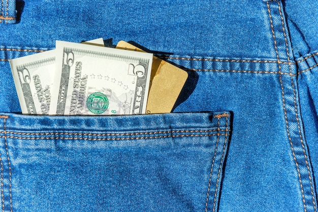 Credit plastic bank card with dollar cash in blue jeans pocket- money concept