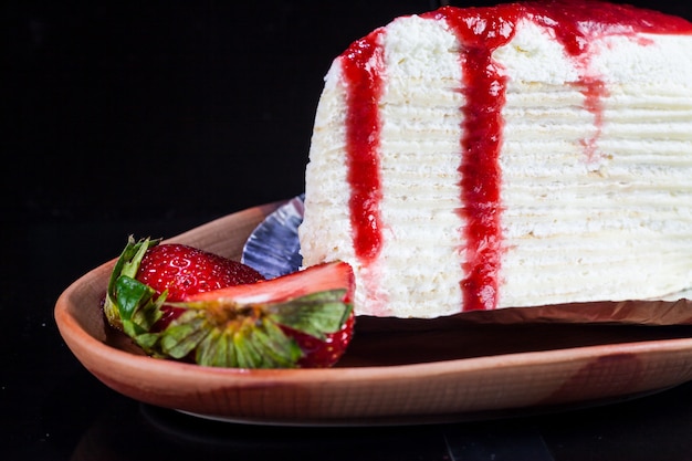 Crepe cake with strawberry sauce and fresh strawberries.