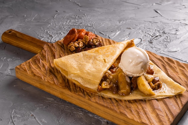 Crepes stuffed with fruit and nuts served with ice cream ball thin pancakes sweet dessert