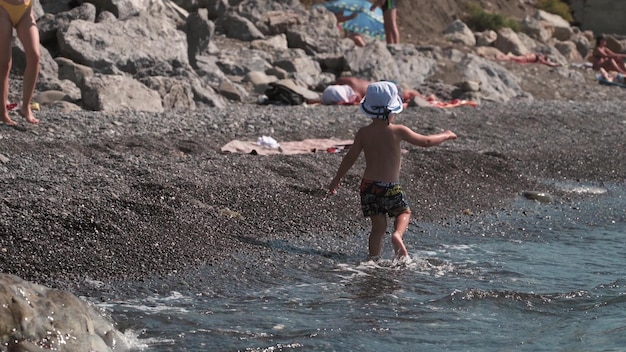 Crimea Morskoe 312021 Cute active boy walking and splashing in the water on the seashore in slow motion Summer vacation on the coast