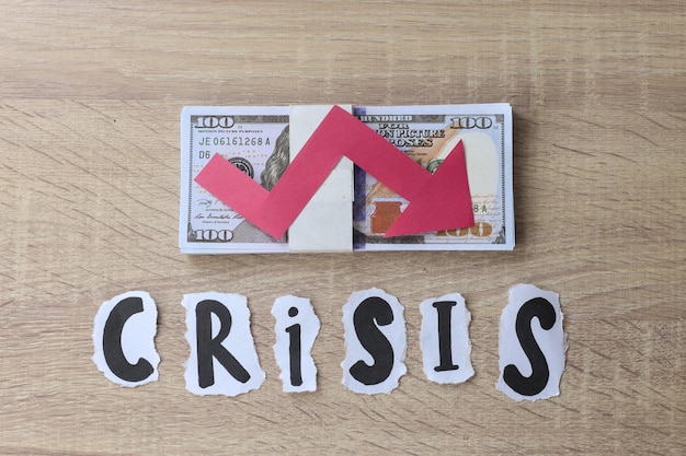 Crisis lettering with red arrow down shape on dollar banknote. Financial crisis concept.