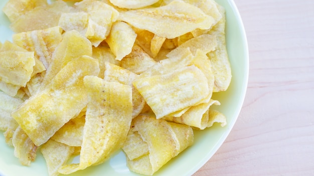 Crispy banana in a yellow plate on wooden background.