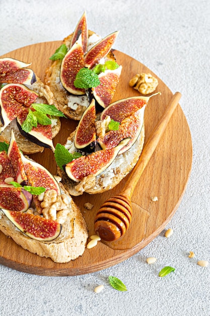 Crispy bruschetta (toast) with soft ricotta, ripe figs, walnuts and pine nuts, mint and honey