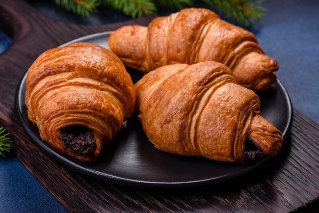 Crispy chocolate croissant with Christmas decorations on wooden cutting board