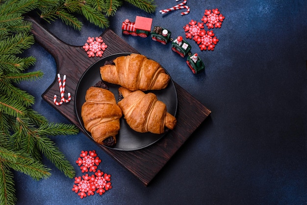 Crispy chocolate croissant with Christmas decorations on wooden cutting board