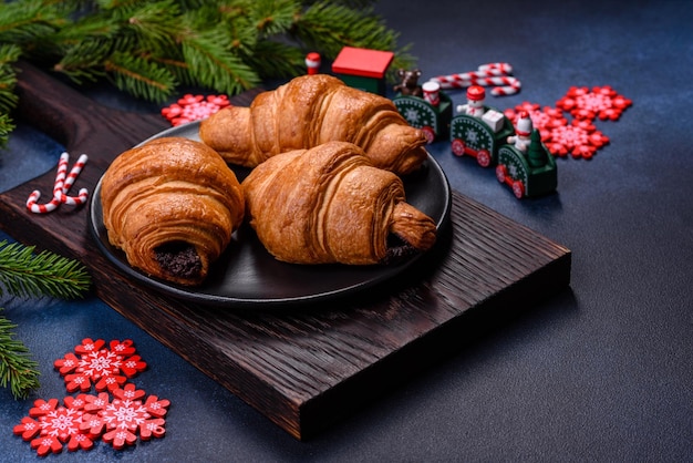 Crispy chocolate croissant with Christmas decorations on wooden cutting board