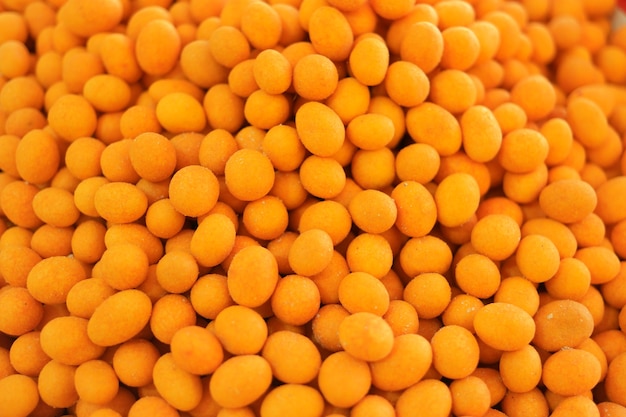 Crispy coated peanuts background. Pile of yellow edible balls close up. Traditional oriental dessert.