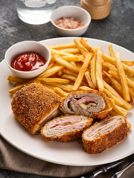 Crispy Cordon Blue Chicken fillet roll with ham and cheese Served in white plate on grey background