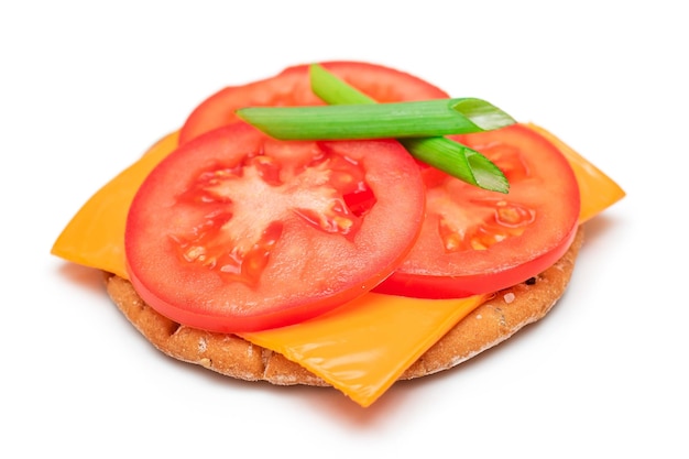 Crispy cracker sandwich with tomato cheese and green onions isolated