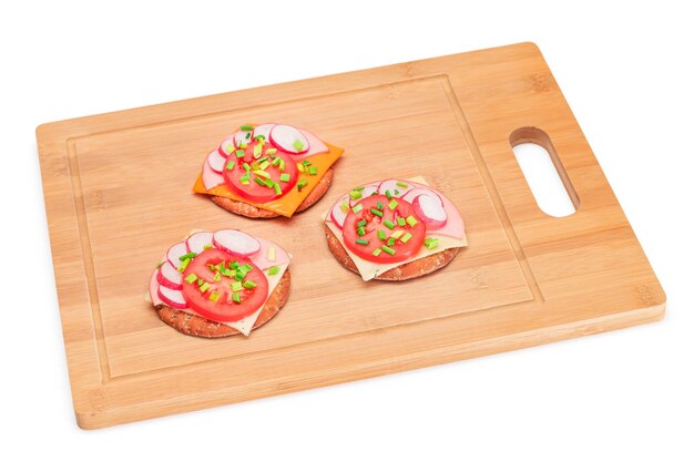 Crispy cracker sandwiches with tomato sausage cheese green onions and radish isolated