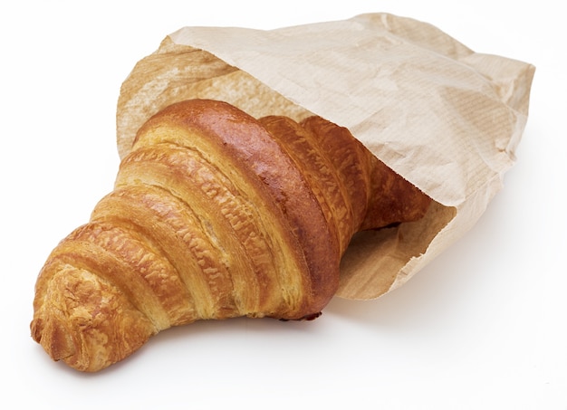 Crispy fresh butter croissant. In a paper bag. Isolated on white background.