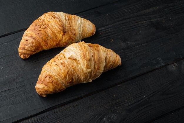 Crispy fresh croissants set, on black wooden table background