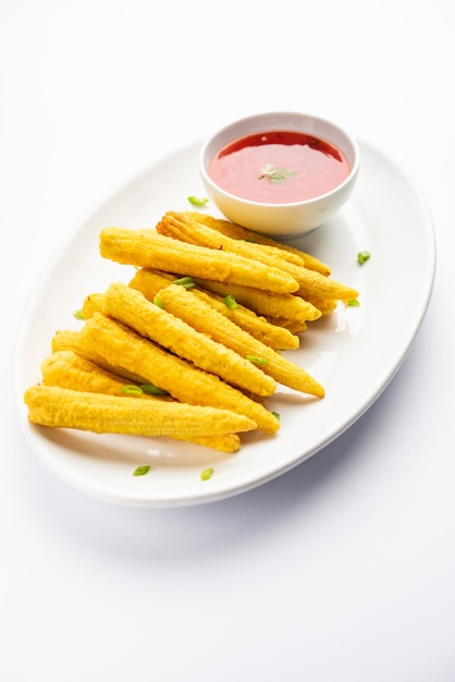 Crispy fried baby corn pakoda pakora or Baby corn fritters served with ketchup Indian food