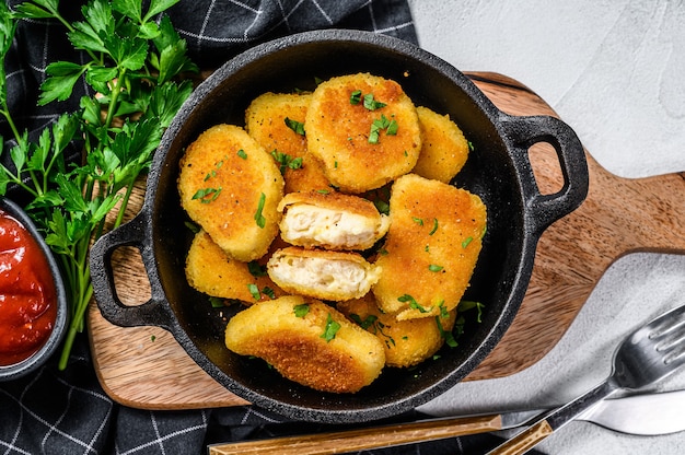 Crispy fried chicken nuggets in a pan with ketchup and herbs