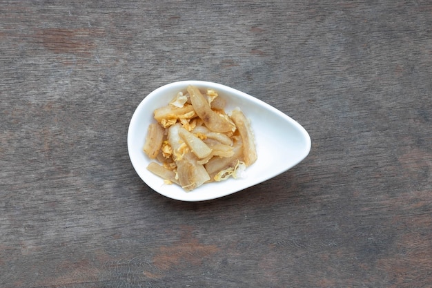 Crispy fried pock and garlic in white ceramic cup on wooden table Thai food