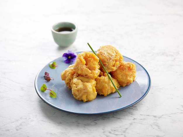 Crispy fried Prawns tossed with Salted Egg Yolk served in a dish with chopsticks side view on grey background