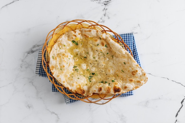 Crispy garlic naan in a basket isolated on napkin side view on grey background famous indian and pakistani food