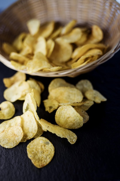 Crispy potato chips in a wicker bowl on old kitchen table