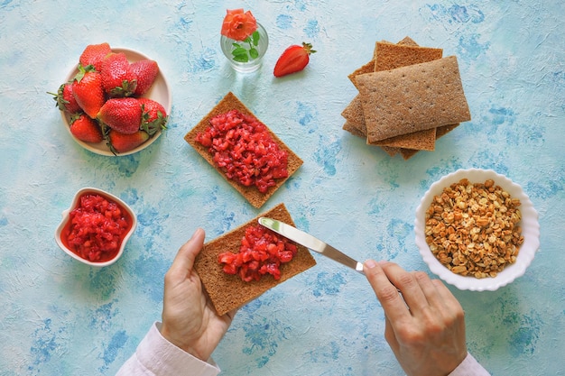 Crispy rye with strawberry jam. Strawberry toast on rye bread. Vegetarian sweet breakfast on a white on a blue surface