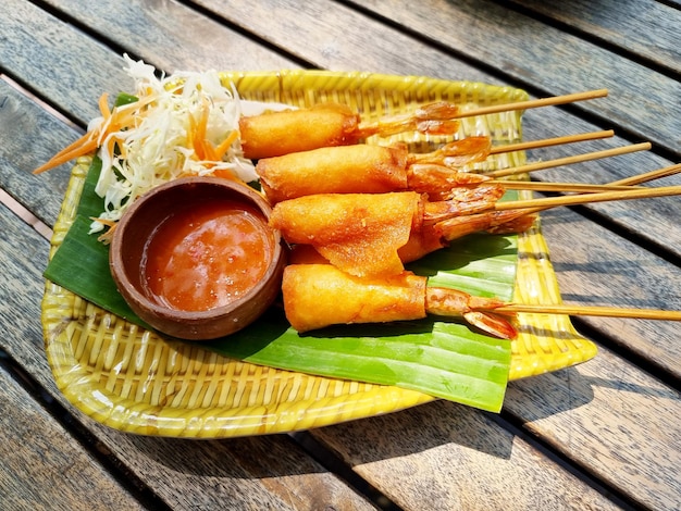 Crispy shrimp spring rolls with sweet sauce on a wooden table