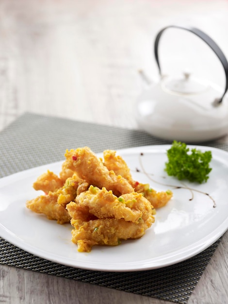 Crispy Squid tossed with Salted Egg Yolk served in a dish side view on grey background