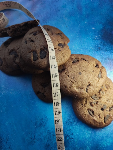 crispy sweet round chocolate chip cookies and measuring tape weight loss on a blue background