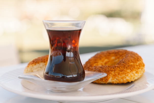 Crispy turkish traditional bagel simit with sesame and glass of turkish black tea