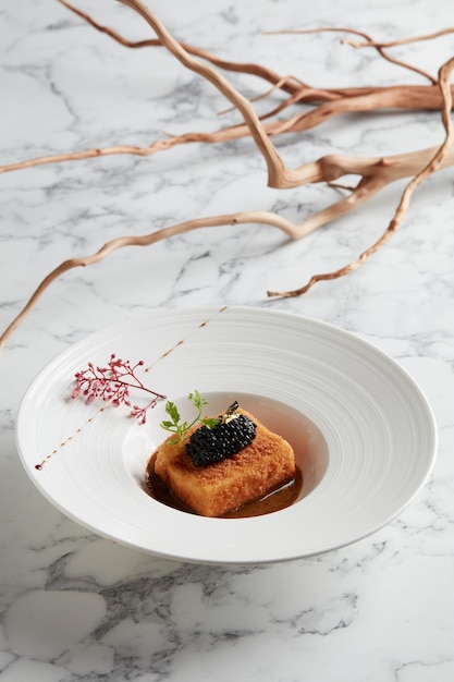 Crispyfried Tofu in Truffle Sauce with Black Truffle Pearl served in a dish isolated on grey background