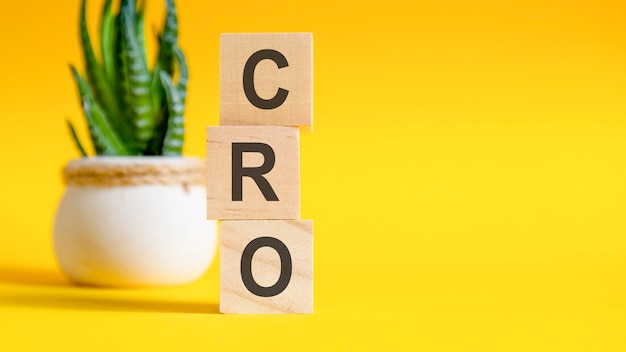 CRO concept with wooden blocks on table, yellow background