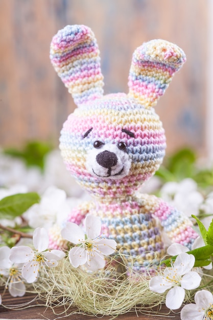 Crochet bunny on the background of delicate cherry flowers.