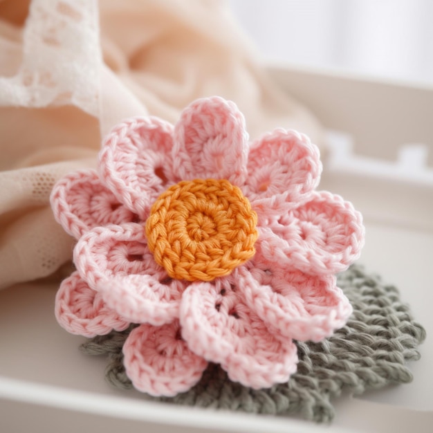 A crochet flower is on a tray with a cloth in the background.