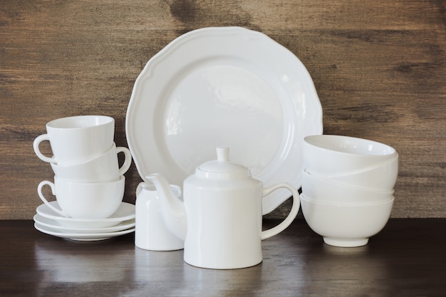 Crockery, porcelain, white utensils and other different stuff on wooden tabletop. 