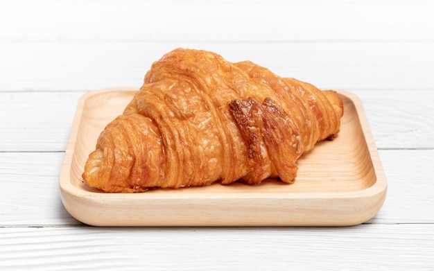 Croissant the delicious bakery in wooden plate on vintage white wooden background