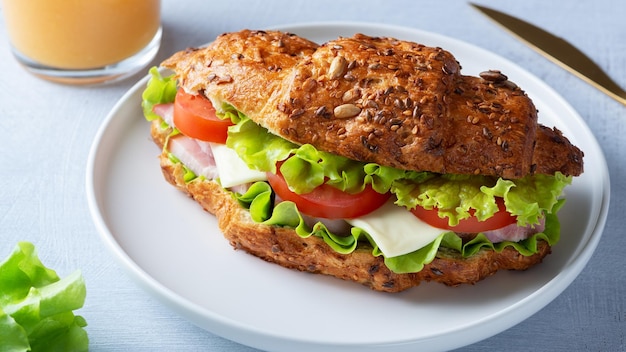 Croissant sandwich with meat vegetables and cheese white background Breakfast food concept